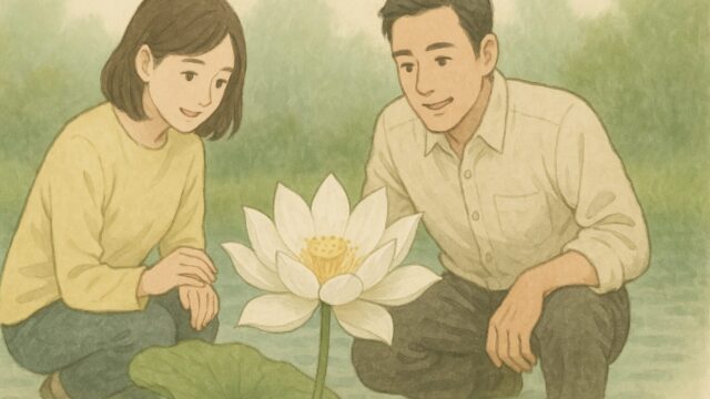 池の浅瀬で咲く白い蓮華の花を、現代の服装をした日本人の男女が優しく見つめている様子。背景には淡い緑の自然が広がり、全体的に穏やかで落ち着いた雰囲気の絵。