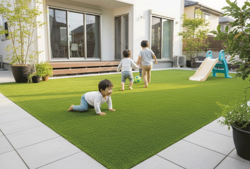 明るく親しみやすい写真スタイル。 人工芝の庭で遊ぶ子供たち（顔は写らない構図）。 安全で柔らかい印象。 日本の戸建て住宅。