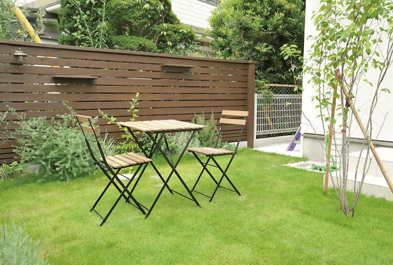 明るい庭で、タブレットを見ながら施主とデザインの相談をしている親しみやすい造園のプロ。