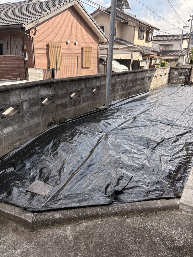 造園現場でブロック塀の際まで黒い防草シートを敷いた施工事例
