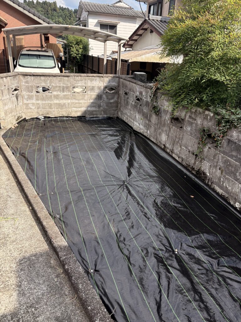 造園現場で庭全体に黒い防草シートを敷いた施工事例