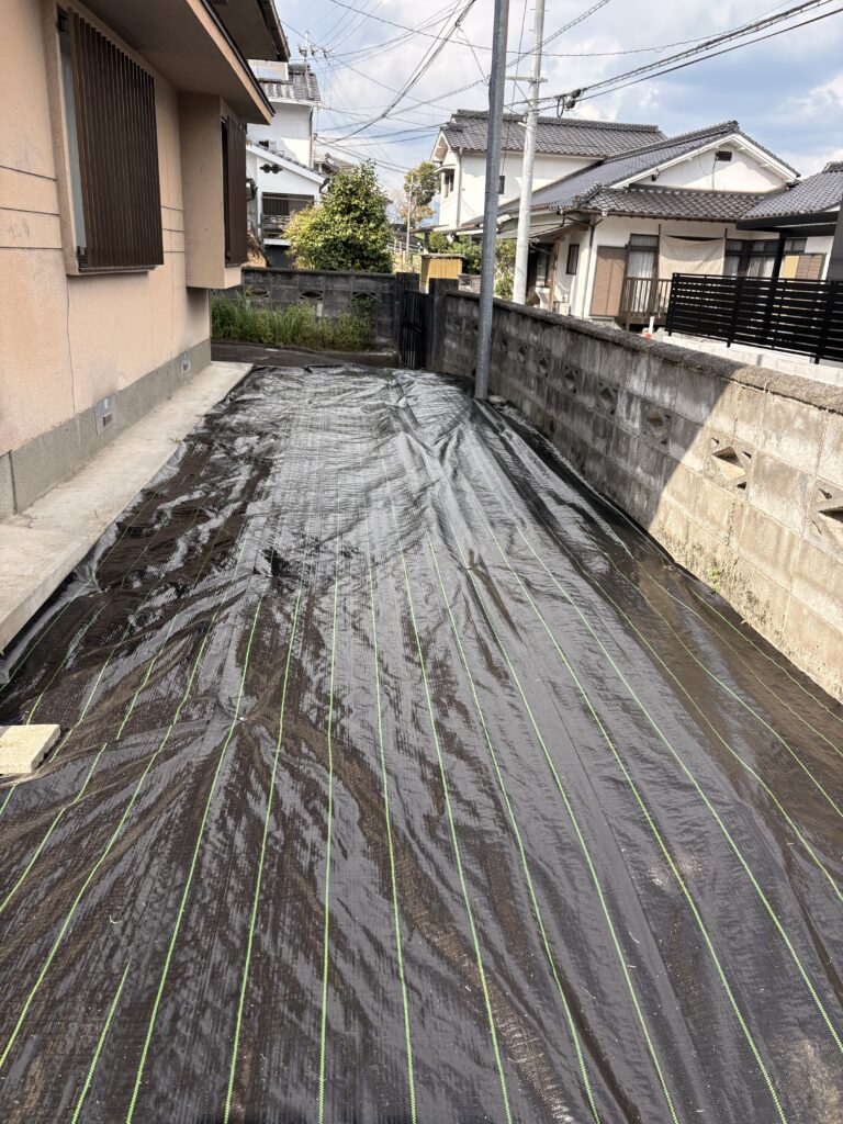 造園現場で奥行きのある細長い側庭に防草シートを敷いた施工事例